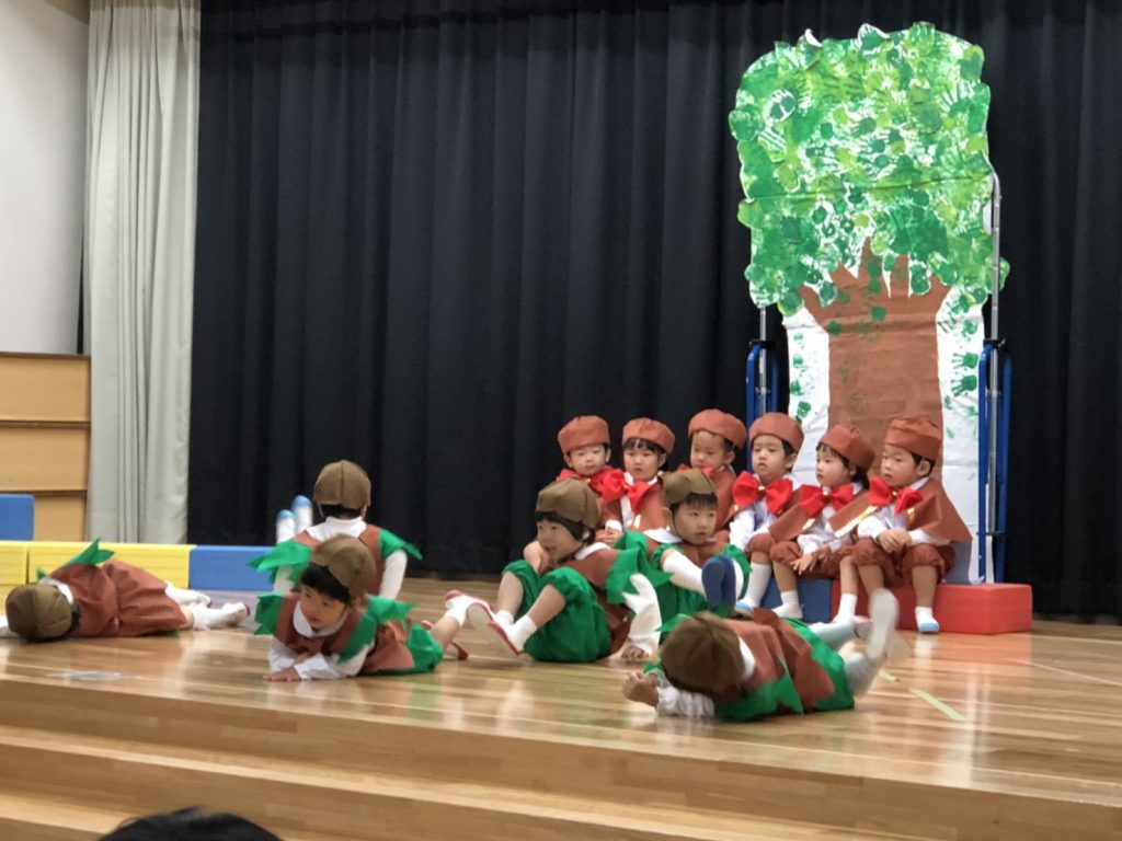 こども達がどんぐりになって転がっている写真