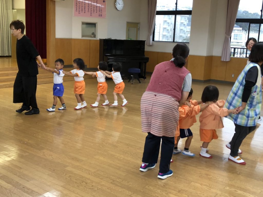 小さい園児さんが繋がって遊んでいる様子の写真