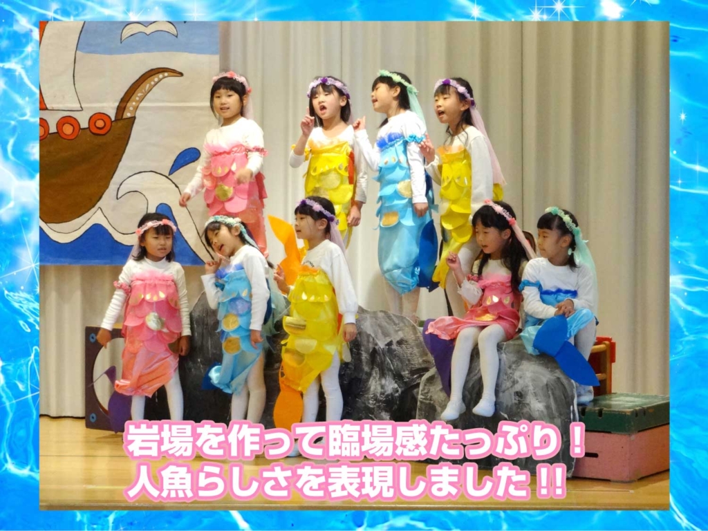 岩場に立った人魚をこども達が演じている写真