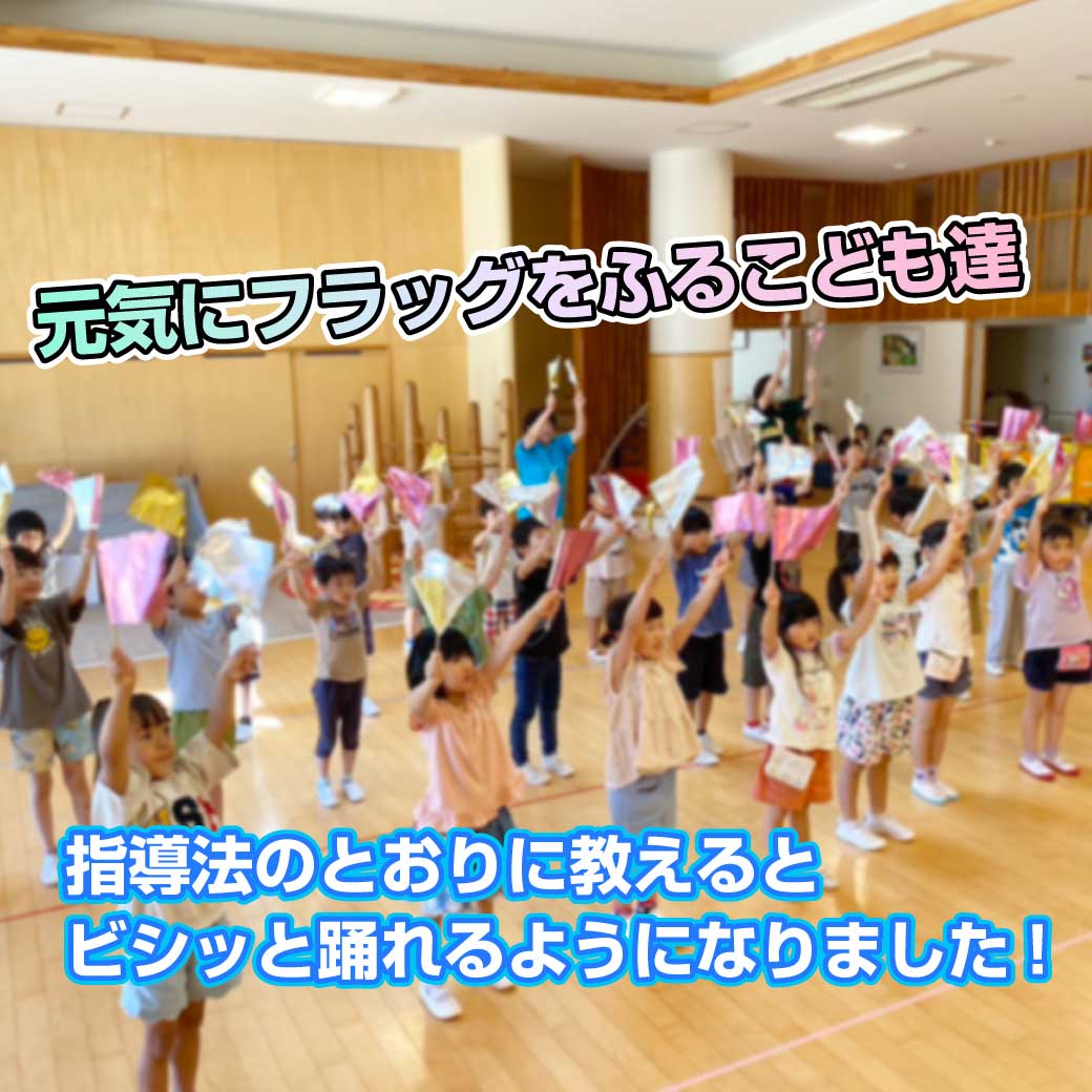 園児達がフラッグを持って元気に踊っている写真